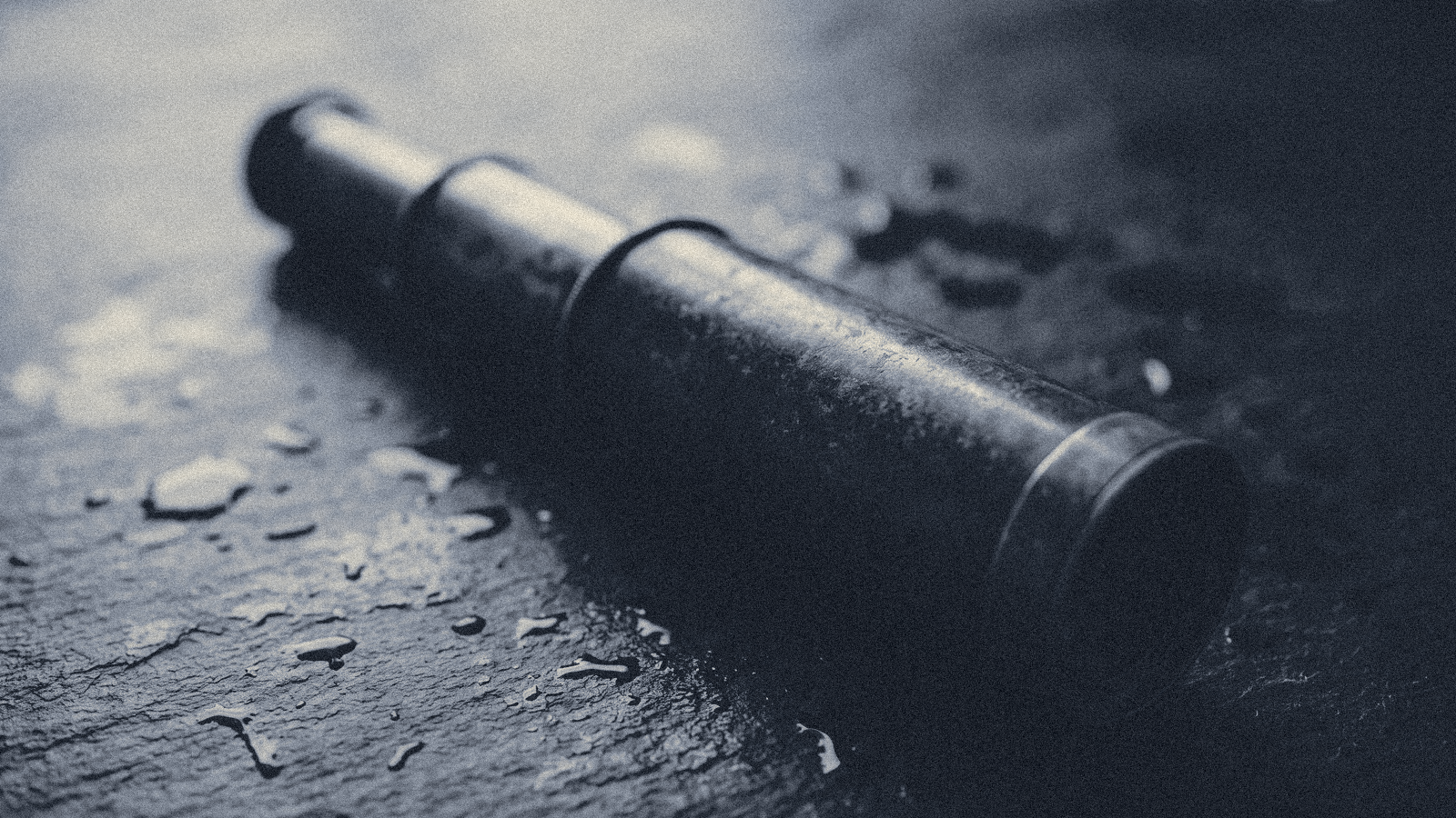 An antique brass telescope tube resting on dark wet slate, seen from above, soft raking light.
