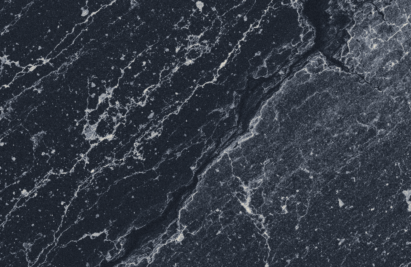 Extreme macro of dark granodiorite: a polished smooth band meeting a rough chiselled band, mineral speckle under raking light.