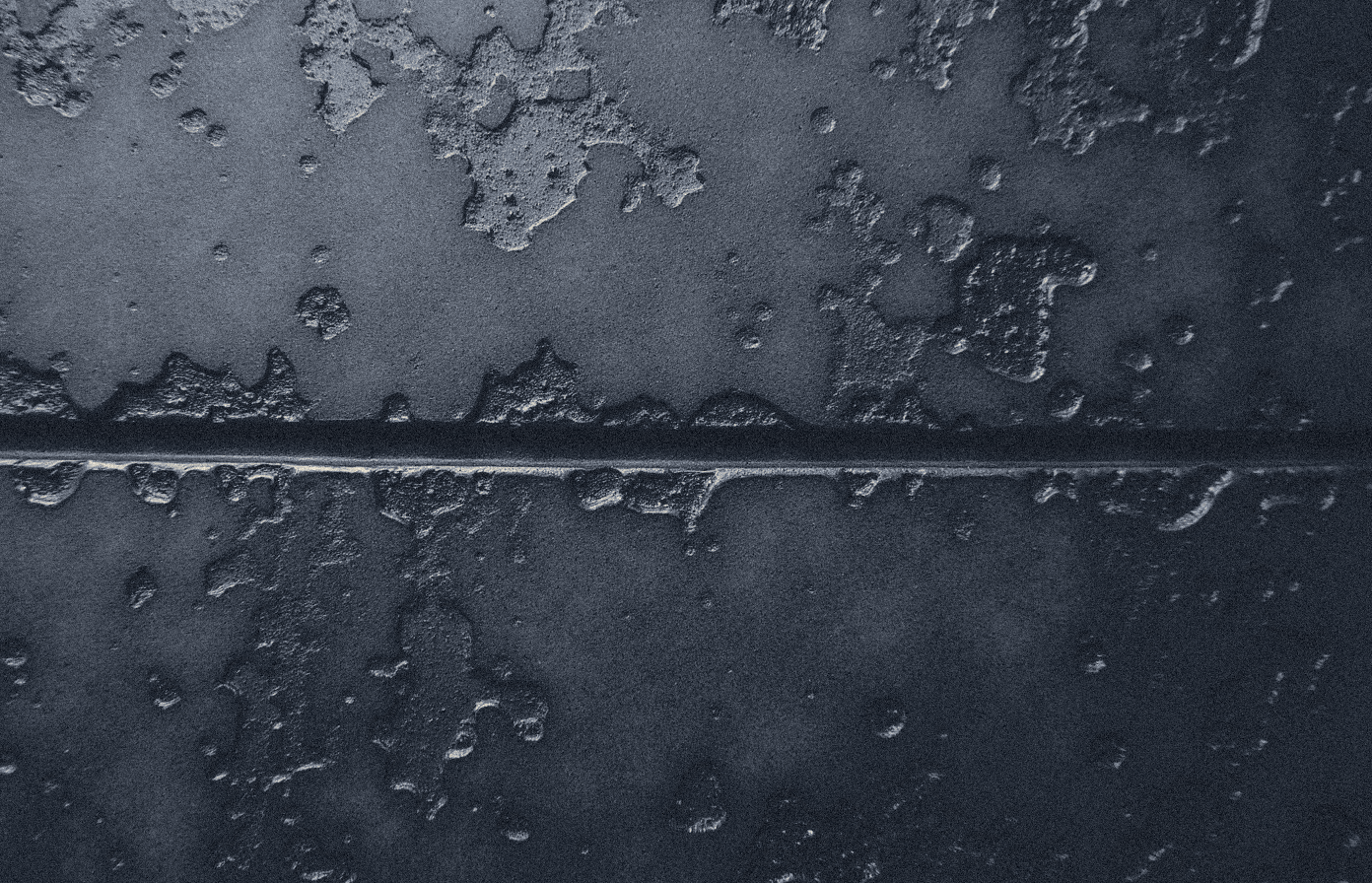 Extreme macro of an ancient cast bronze surface with mottled verdigris patina and a single casting seam, texture only, no figures or text.